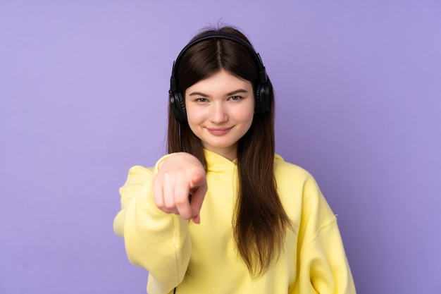 Młoda nastolatek dziewczyna nad purpury ściany słuchającą muzyką