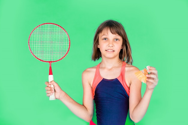 Młoda nastolatek dziewczyna skacze badminton na zielonej ścianie i bawić się