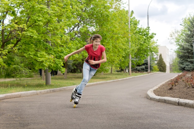 Młoda nastolatka jeździ na rolkach po zakręcie wiejskiej drogi z prędkością