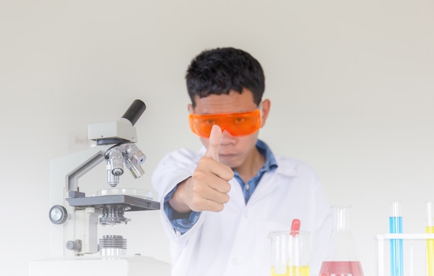 Młoda naukowiec ręka daje kciukowi up jak znakowi sukces, robi chemicznym testom w laboratorium