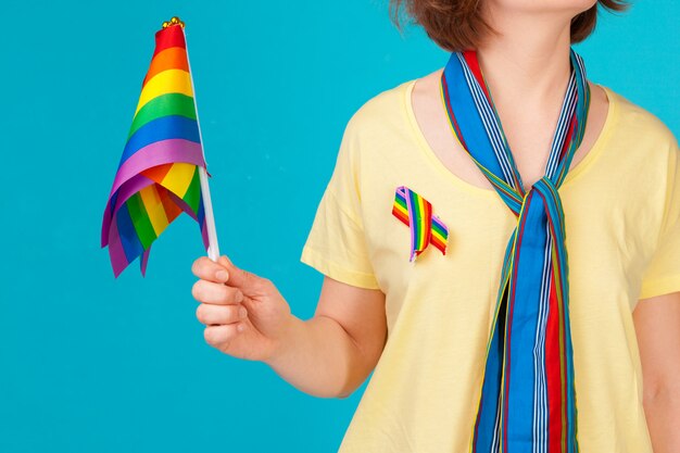 Młoda nierozpoznawalna kobieta trzyma małą flagę LGBT