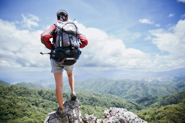 Młoda osoba wędrująca kobieta stojąca na szczycie skały Kobieta z plecakiem patrząca na piękną górę