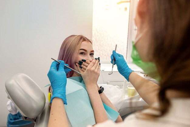Zdjęcie młoda pacjentka siedzi u dentysty i zamyka usta przed dentystą, ponieważ się boi