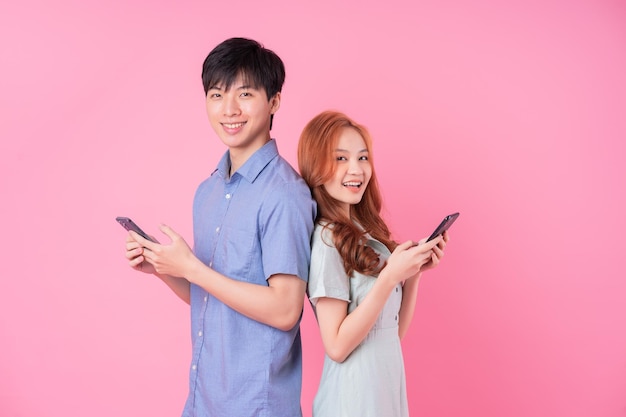 Młoda Para Azjatów Korzystająca Ze Smartfona Na Różowym Tle