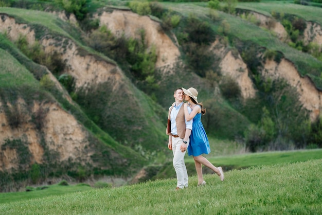 Młoda para, facet i dziewczyna spacerują po zielonych górskich wzgórzach