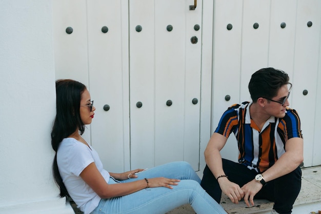 Młoda para hipster w stylowych dżinsach siedzi na ulicy