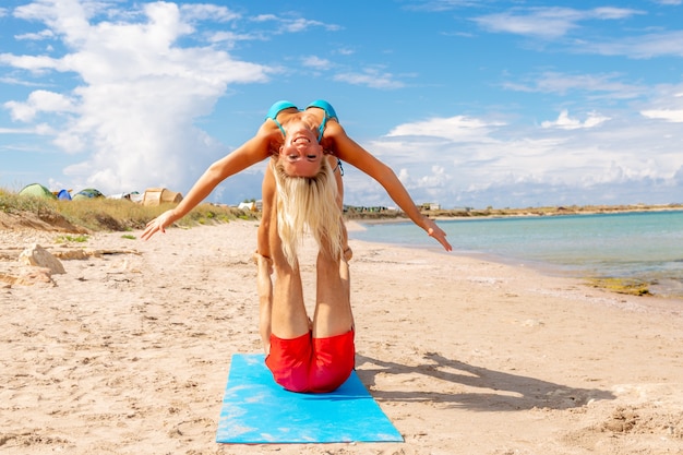 Młoda Para Kobieta I Mężczyźni Na Plaży Razem Robić ćwiczenia Jogi Fitness. Element Acroyoga Dla Siły I Równowagi