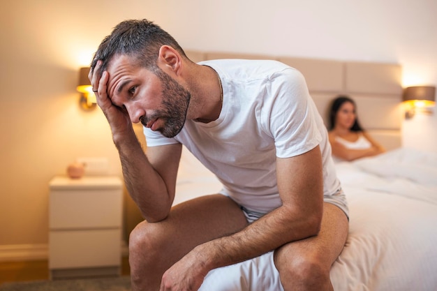 Młoda para ma problem Facet siedzi na łóżku i odwraca wzrok ze swoją dziewczyną w tle Zdenerwowana młoda para ma problemy z seksem