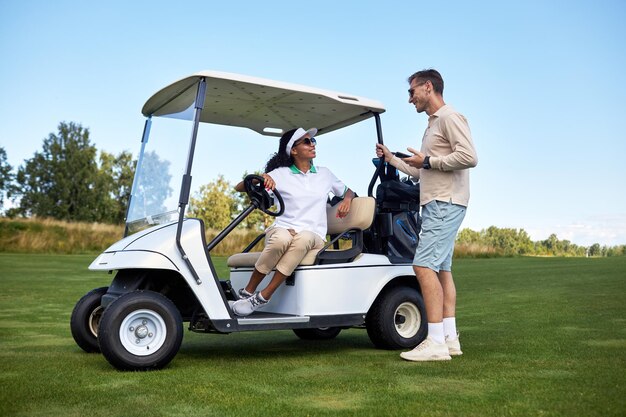 Młoda para na czacie wózkiem golfowym w zielonym polu