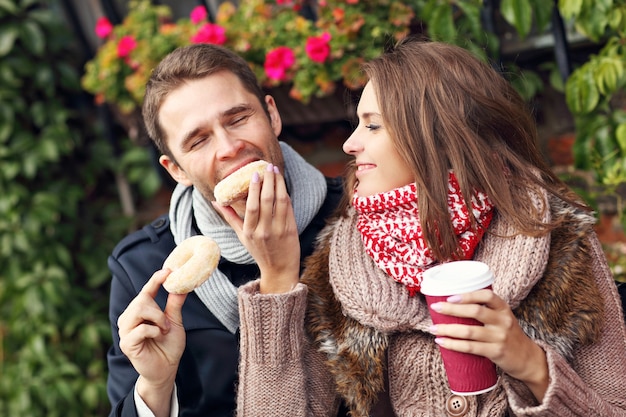 Zdjęcie młoda para na randce w mieście przy kawie i pączkach