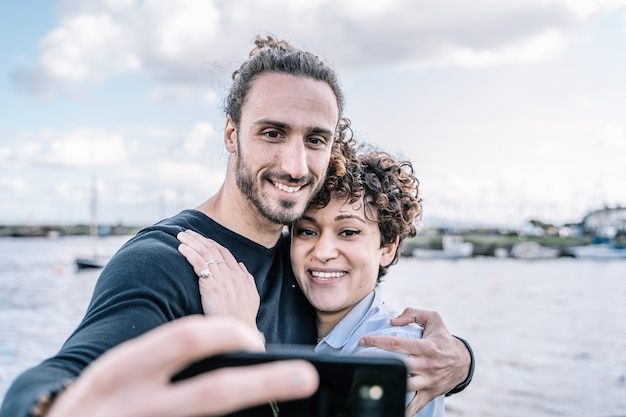 Młoda Para Objęta Ramieniem Robi Selfie Z Nieostrym Portem I Morzem