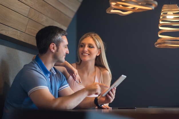 Młoda para przy użyciu komputera typu tablet w luksusowym domu razem, patrząc na ekran, uśmiechając się.