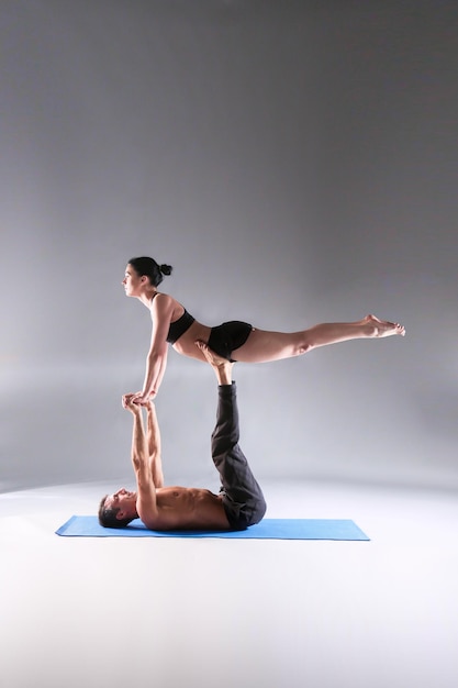 Młoda para razem ćwiczy acro jogę na macie w studio Acroyoga Couple yoga