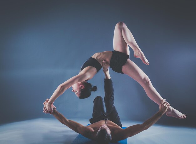 Młoda para razem ćwiczy acro jogę na macie w studio Acroyoga Couple yoga