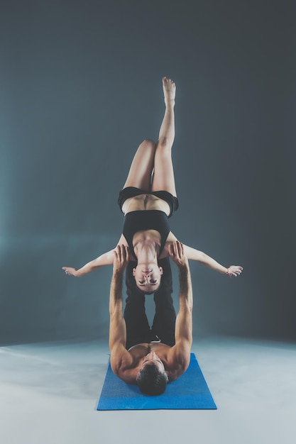 Młoda para razem ćwiczy acro jogę na macie w studio Acroyoga Couple yoga