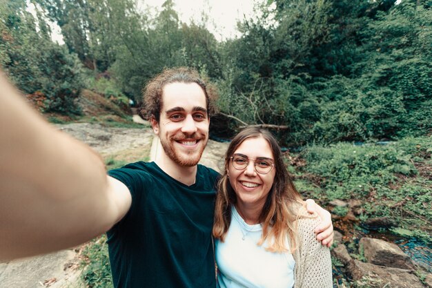Zdjęcie młoda para robi selfie w lesie z uśmiechem