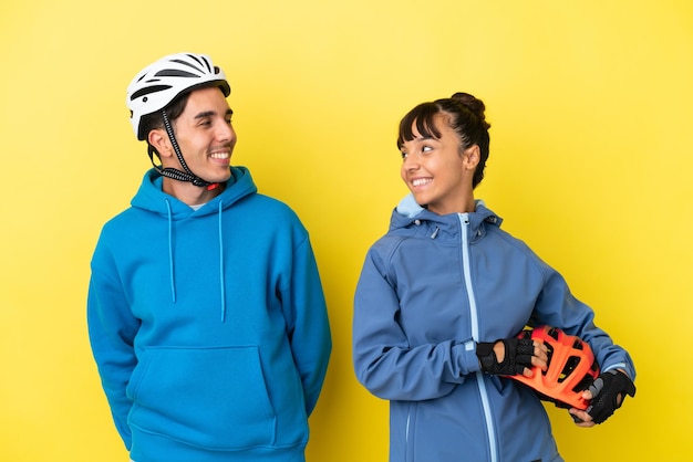 Młoda para rowerzystów na żółtym tle, patrząc przez ramię z uśmiechem