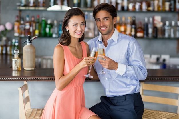 Młoda para siedzi przy barze licznika i opiekania kieliszki szampana