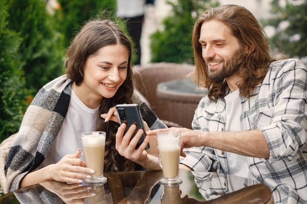 Zdjęcie młoda para siedzi w kawiarni na świeżym powietrzu, ciesząc się kawą i rozmową