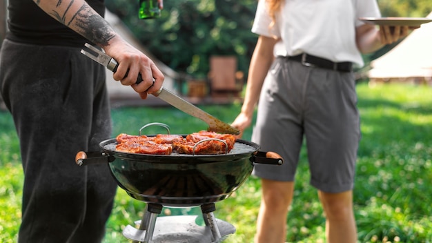 Młoda para smażenia mięsa na grillu. Wokół zieleń. Glamping