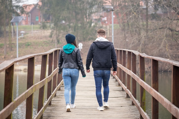 Młoda para spacerująca po starym drewnianym moście w mglisty zimowy dzień nad jeziorem Gebart