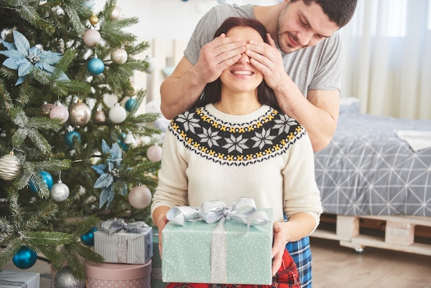 Młoda para świętuje Boże Narodzenie. Mężczyzna nagle podarował żonie prezent. Pojęcie szczęścia i dobrego samopoczucia rodziny