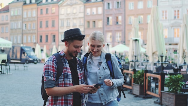 Młoda para turystów korzystających ze smartfona i podziwiających piękną okolicę. Wcześnie rano wybierają się na zwiedzanie.