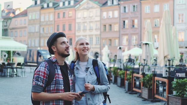 Młoda Para Turystów Korzystających Ze Smartfona I Podziwiających Piękną Okolicę. Wcześnie Rano Wybierają Się Na Zwiedzanie.