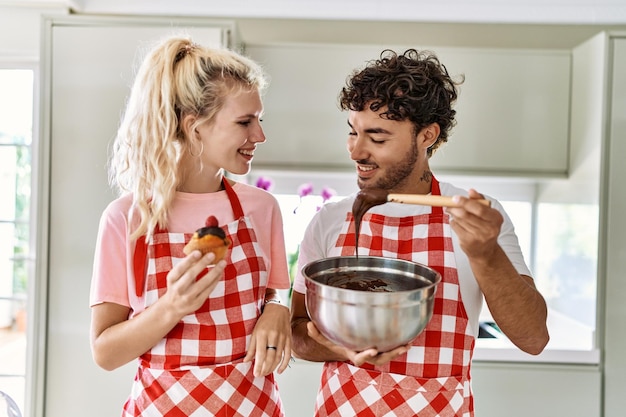 Młoda para uśmiecha się szczęśliwych słodyczy do gotowania w kuchni