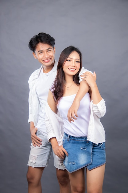 Młoda para w białej koszuli i niebieskich dżinsach pozuje do fotomęskiej i kobiecej mody promocyjnej