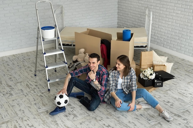 Zdjęcie młoda para w nowym domu relaks na tle dużych pudeł. koncepcja parapetówki, zaczęła mieszkać razem.