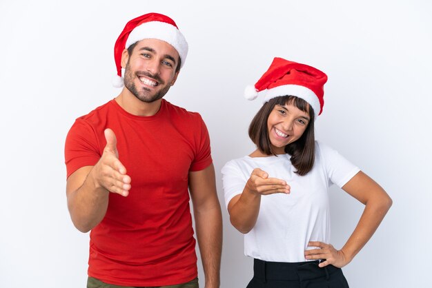Młoda para w świątecznym kapeluszu na białym tle, ściskając ręce, aby zamknąć dobrą ofertę