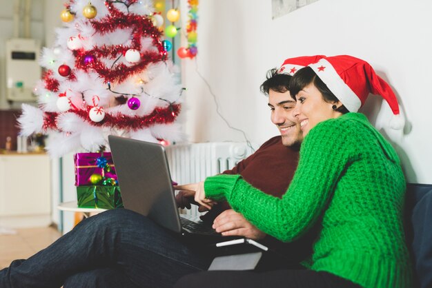 Młoda para z laptopem w czasie świąt Bożego Narodzenia
