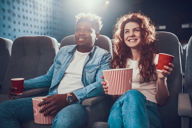 Młoda para z popcornem siedzi w kinie.