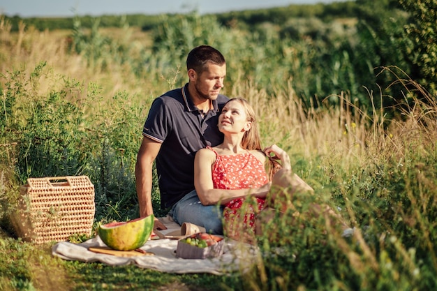 Młoda para zakochana na letnim pikniku z arbuzową zakochaną parą siedzącą nad rzeką i rozmawiającą