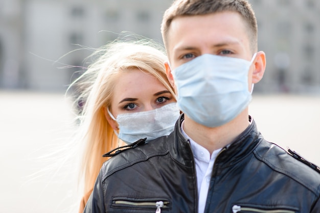 Młoda para zakochana w ochronnej masce medycznej na twarzy na zewnątrz przy ulicy. Facet i dziewczyna w ochronie przed wirusami.
