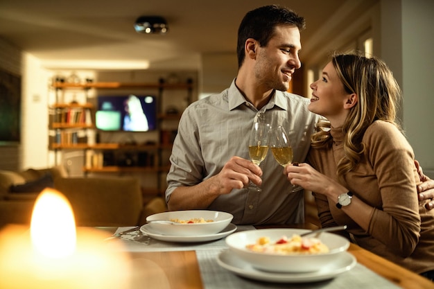 Młoda para zakochana w toastach z szampanem, siedząca blisko siebie przy stole