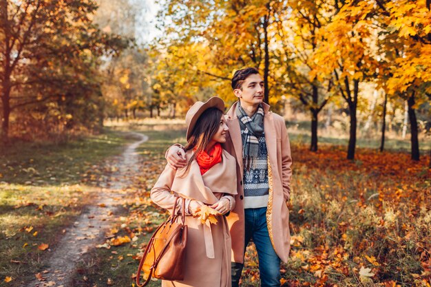 Młoda para zakochanych spacery w lesie jesienią wśród kolorowych drzew. Mężczyzna i kobieta przytulanie na zewnątrz o zachodzie słońca