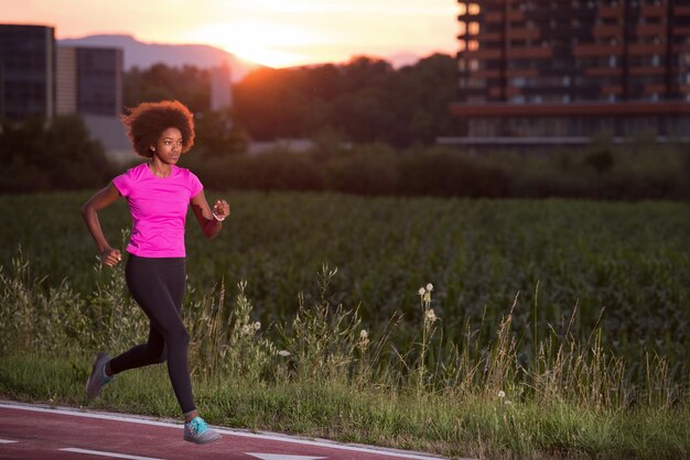 młoda piękna Afroamerykanka lubi biegać poza pięknym letnim wieczorem w mieście