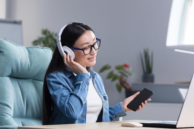 Młoda Piękna Azjatycka Kobieta Słucha Muzyki W Biurze Przy Użyciu Telefonu I Aplikacji Muzycznej Bizneswoman Ze Słuchawkami Odpoczywającymi