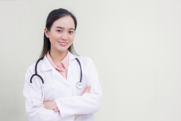 Młoda piękna azjatycka lekarka Stojąca z rękami skrzyżowanymi szczęśliwa i uśmiechnięta w szpitalu