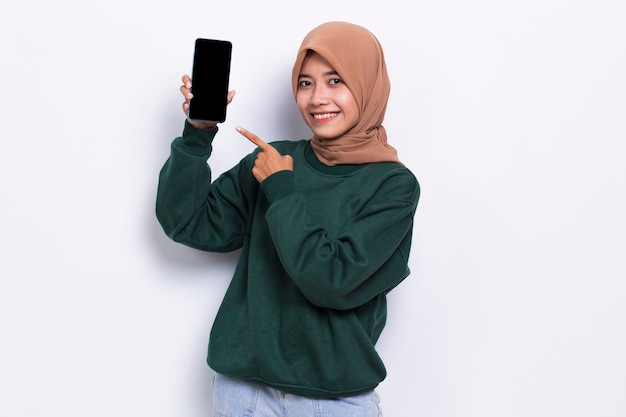 Młoda piękna azjatycka muzułmańska kobieta demonstruje telefon komórkowy na białym tle