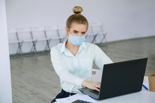 Zdjęcie młoda piękna bizneswoman pracuje w masce ochronnej z laptopem koncepcja sukcesu i pracy online