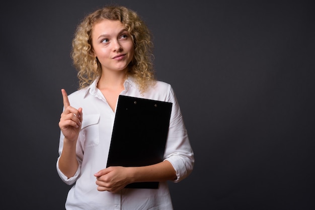 Młoda piękna bizneswoman trzyma schowek z kręconymi blond włosami