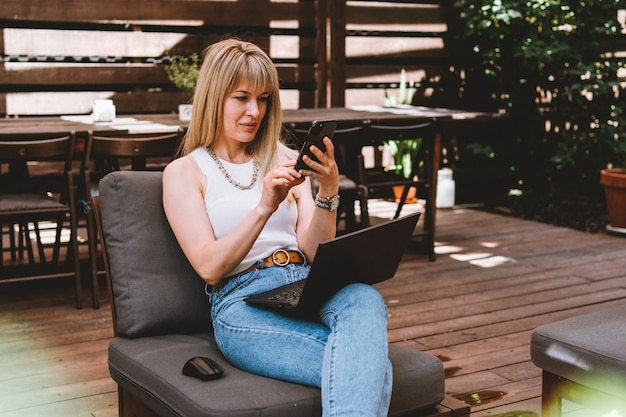 Młoda piękna blondynka pracuje na laptopie i rozmawia przez telefon w przytulnej przestrzeni coworkingowej