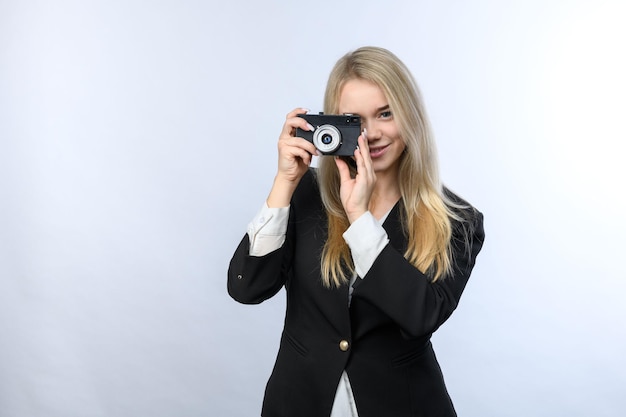 Młoda piękna blondynka trzyma starą kamerę filmową na białym tle