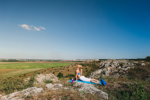 Młoda piękna blondynki kobieta robi joga ćwiczy na skale. Stanie na rękach. Siłownia fitness i sporty na świeżym powietrzu