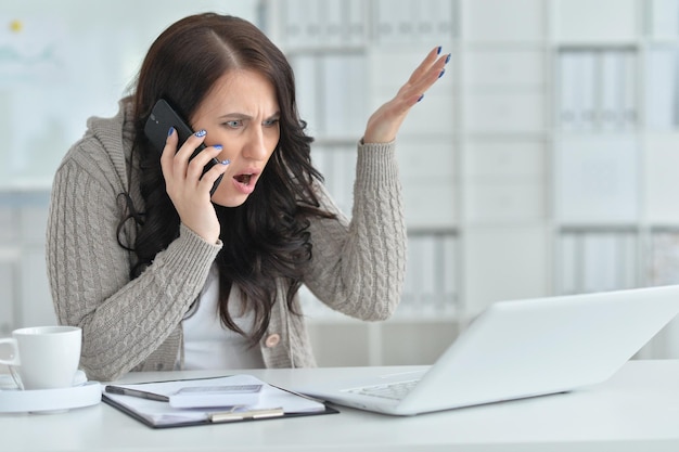 Młoda piękna brunetka kobieta pracuje w biurze przy użyciu laptopa