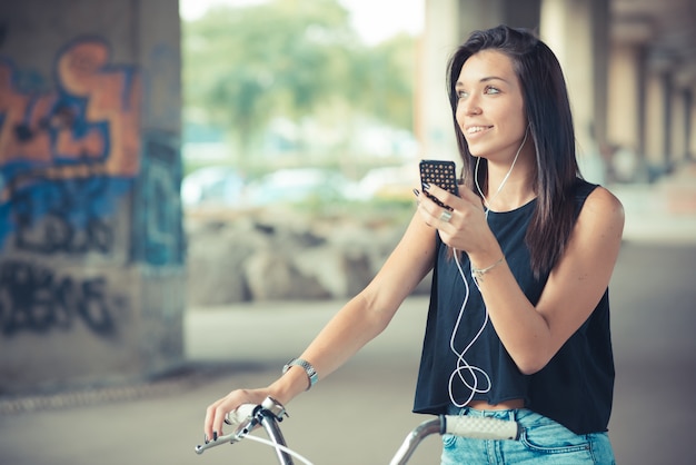 młoda piękna brunetka proste włosy kobieta za pomocą roweru i słuchania muzyki