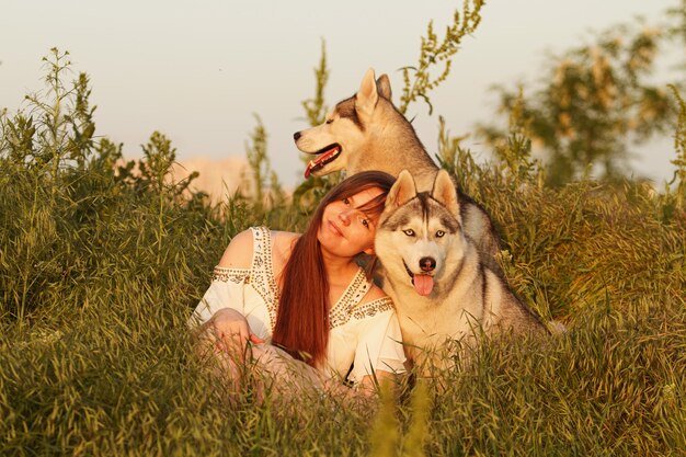 Młoda piękna dziewczyna bawić się z psem. Zabawa z psem na boisku. Syberyjski husky.